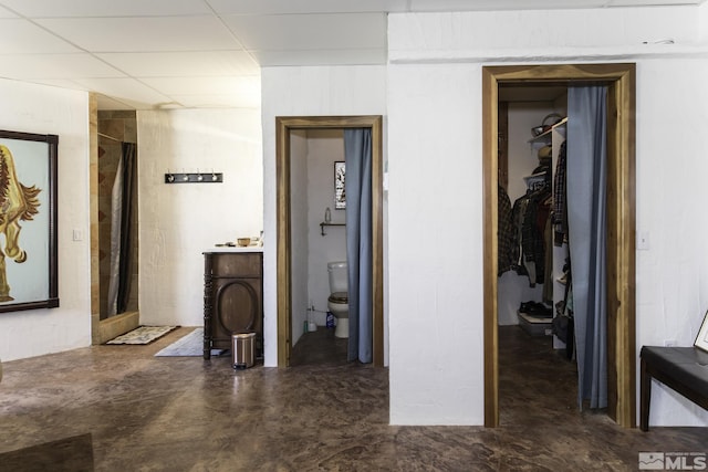 corridor with a drop ceiling and concrete floors