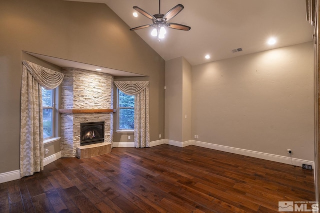 unfurnished living room with a healthy amount of sunlight, wood-type flooring, visible vents, and a stone fireplace