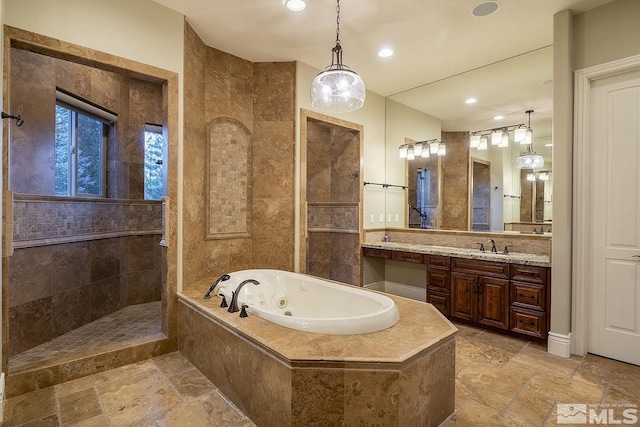 full bathroom featuring stone tile floors, recessed lighting, vanity, a walk in shower, and a tub with jets