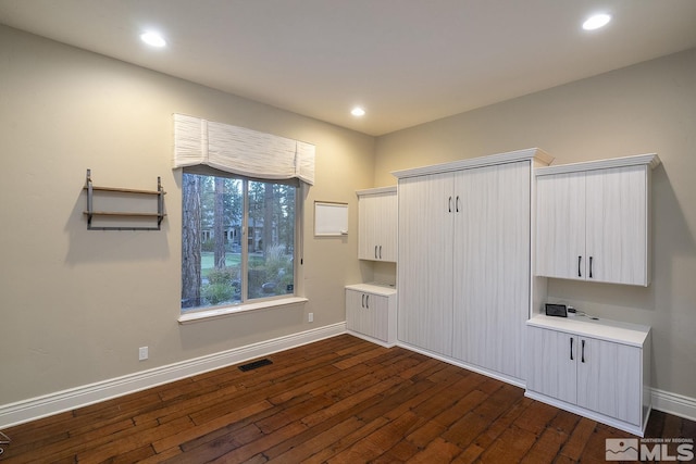 interior space with light countertops, dark wood-type flooring, and baseboards