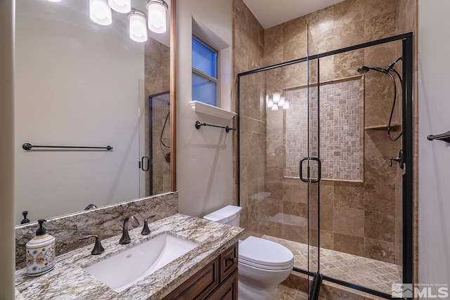 full bathroom with vanity, a shower stall, and toilet