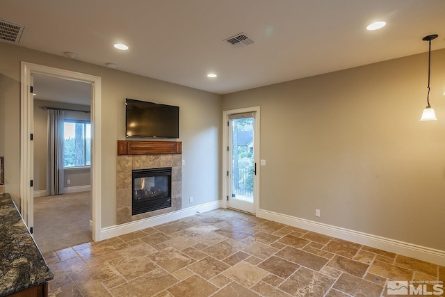 unfurnished living room with stone tile flooring, a fireplace, visible vents, and baseboards