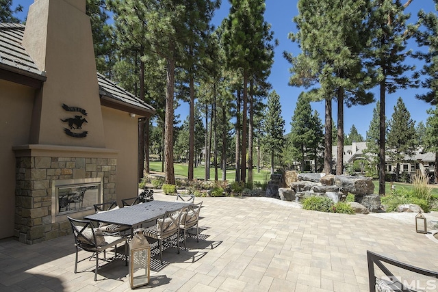 view of patio with an outdoor stone fireplace and outdoor dining space