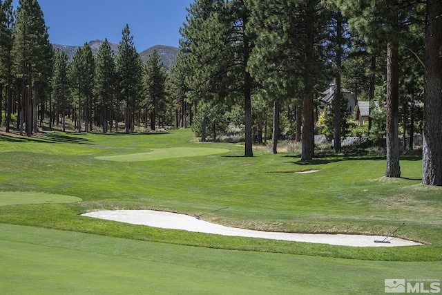 view of property's community with view of golf course, a lawn, and a mountain view