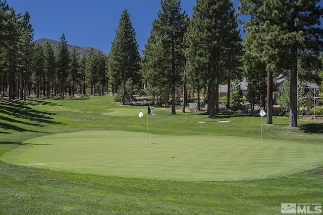 surrounding community featuring view of golf course, a mountain view, and a lawn