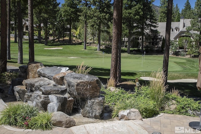 view of community with view of golf course and a lawn