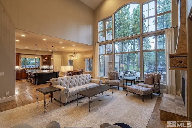 living area featuring high vaulted ceiling, recessed lighting, a fireplace, and stone tile floors