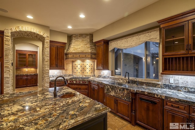 kitchen featuring tasteful backsplash, stainless steel gas cooktop, custom range hood, and a sink