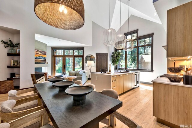 kitchen featuring light wood-type flooring, hanging light fixtures, high vaulted ceiling, and an inviting chandelier