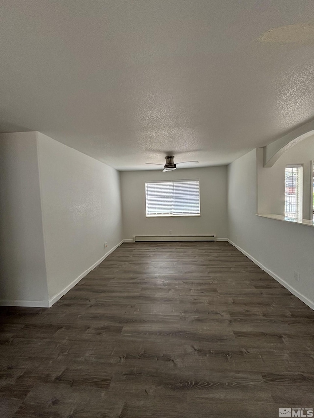 unfurnished room with a baseboard heating unit, baseboards, dark wood-type flooring, and a textured ceiling