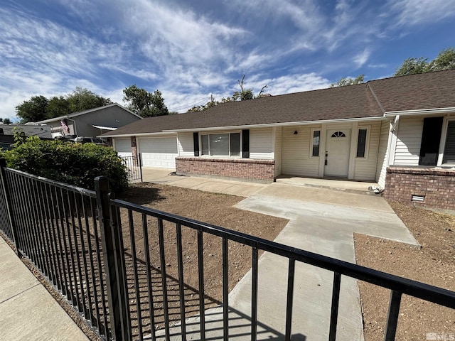 ranch-style house featuring a garage, brick siding, covered porch, and fence