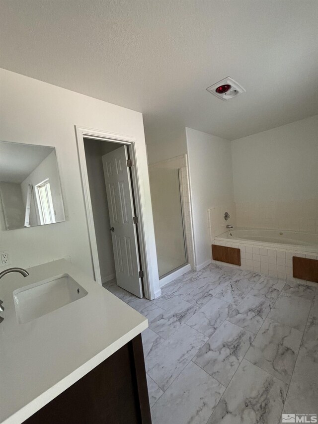 bathroom featuring a textured ceiling, vanity, and separate shower and tub