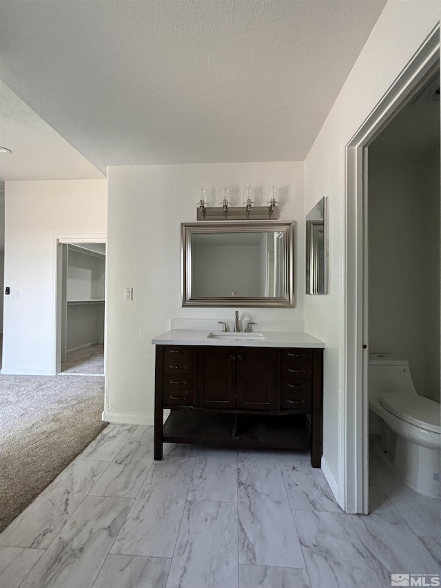 bathroom featuring baseboards, toilet, vanity, marble finish floor, and a textured ceiling