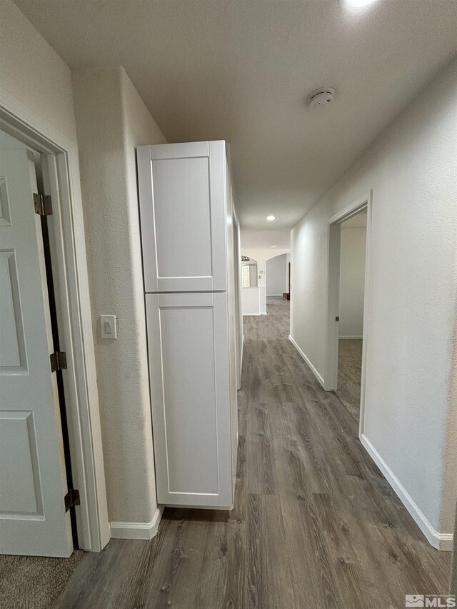 hallway featuring dark wood-type flooring and baseboards