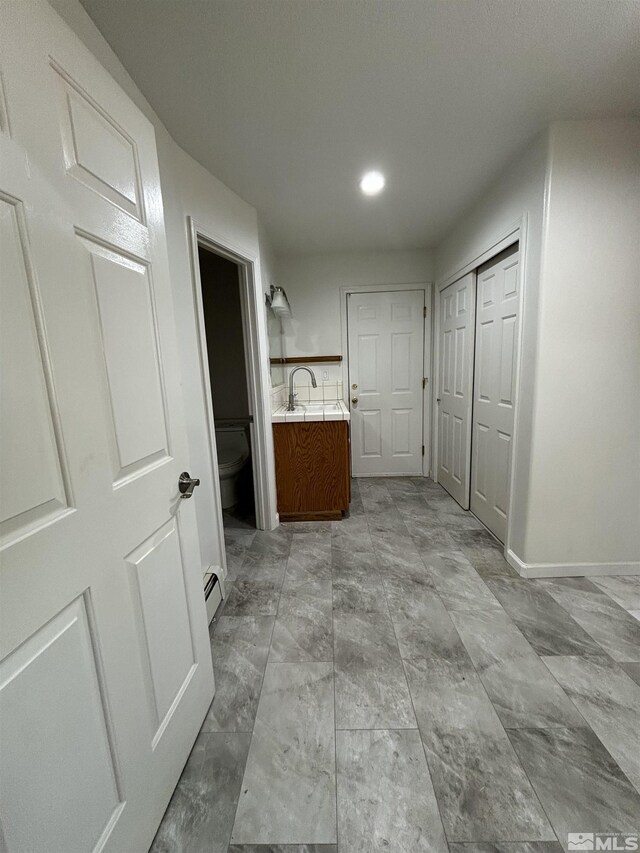 corridor featuring a baseboard heating unit and sink