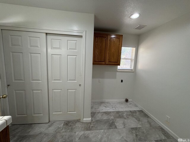 washroom featuring a textured ceiling, cabinets, and hookup for an electric dryer