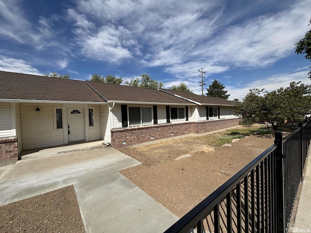 view of front of home featuring brick siding, a shingled roof, and fence