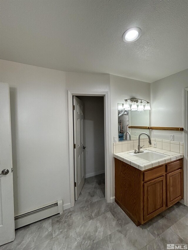 bathroom featuring a baseboard radiator, a textured ceiling, and vanity