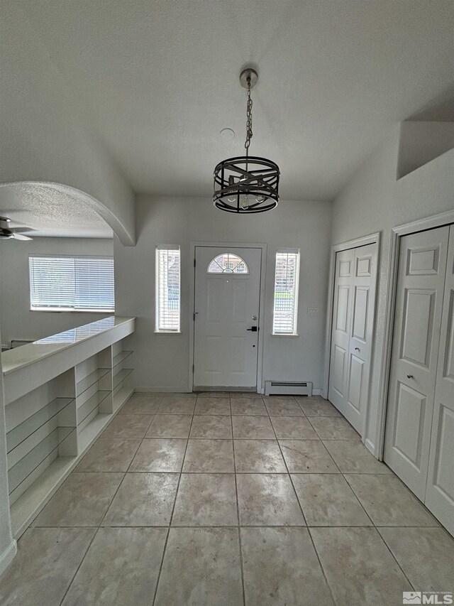 entrance foyer featuring ceiling fan, light tile patterned floors, baseboard heating, and a textured ceiling