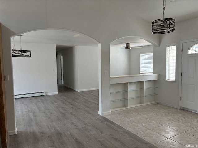 foyer with ceiling fan with notable chandelier, wood finished floors, arched walkways, a baseboard radiator, and baseboards
