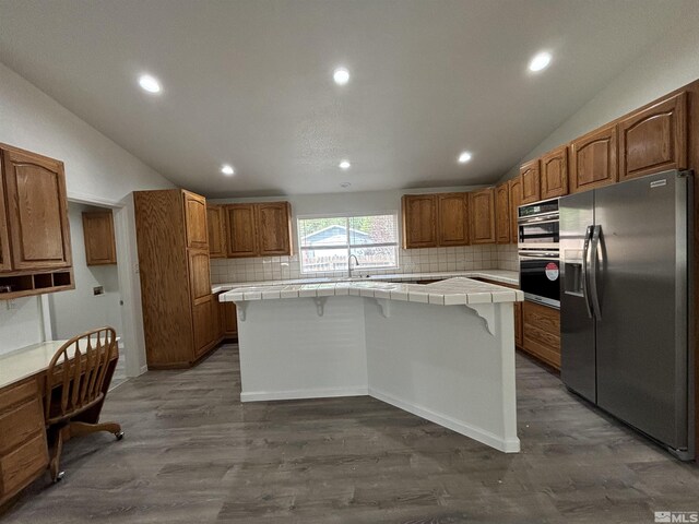 kitchen with a center island, stainless steel appliances, tile counters, and dark hardwood / wood-style floors