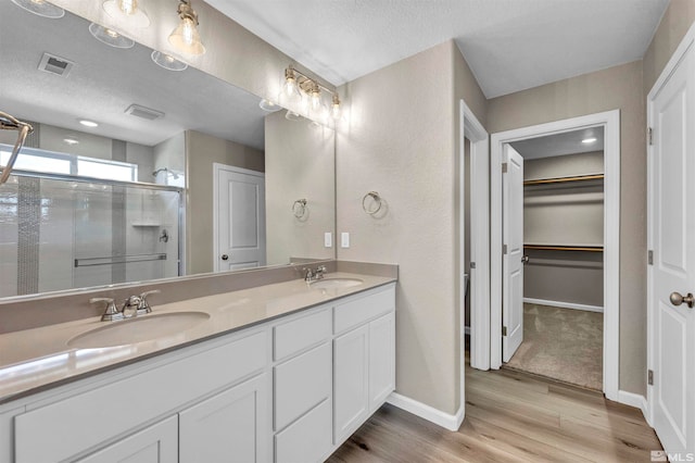 bathroom with hardwood / wood-style floors, vanity, a shower with shower door, and a textured ceiling