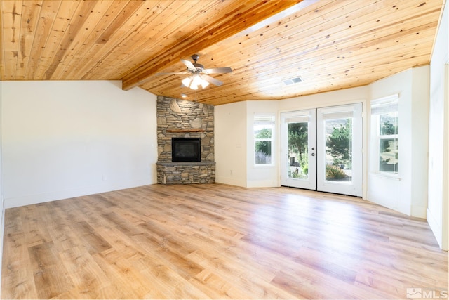 unfurnished living room with french doors, lofted ceiling with beams, a stone fireplace, ceiling fan, and light hardwood / wood-style floors