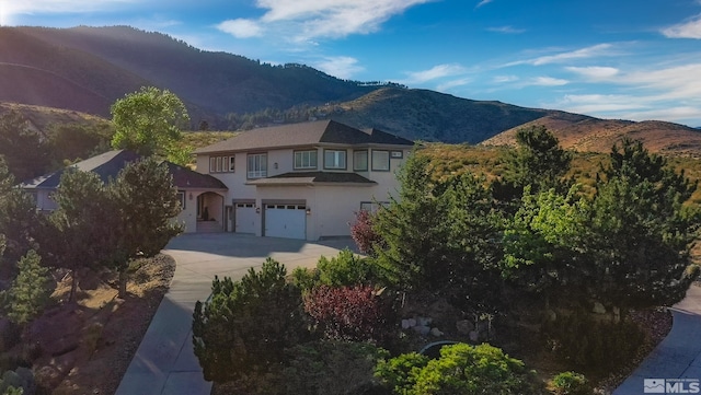 view of front of property with a mountain view, stucco siding, an attached garage, and concrete driveway