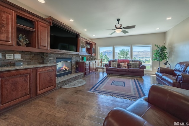 living room with ceiling fan, a fireplace, and dark hardwood / wood-style flooring