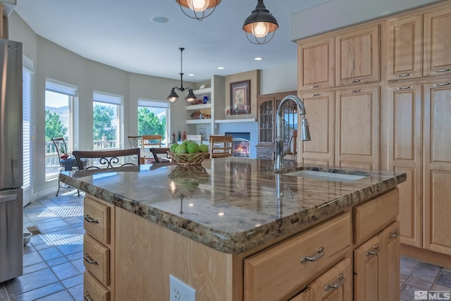 kitchen with light stone counters, a center island, pendant lighting, and sink