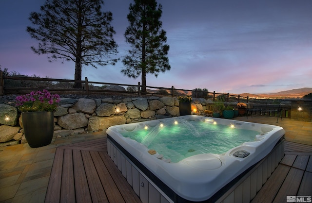 pool at dusk featuring a mountain view and a patio