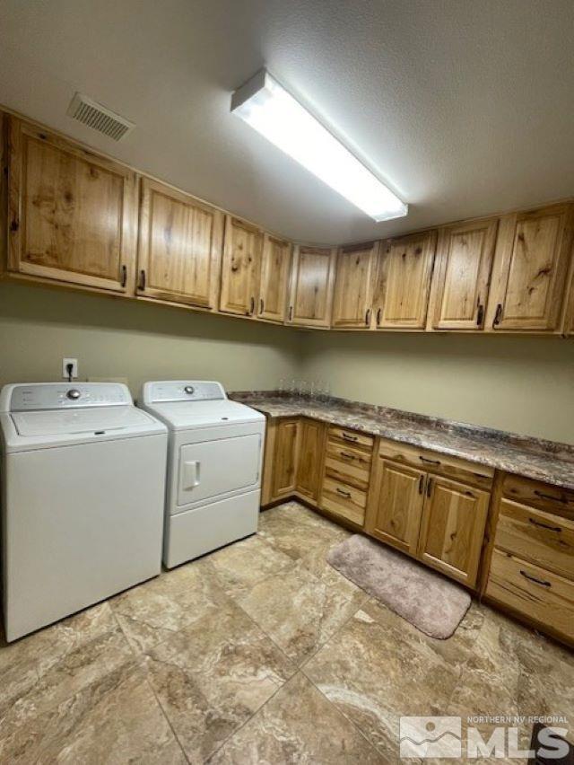 clothes washing area with washing machine and clothes dryer and cabinets