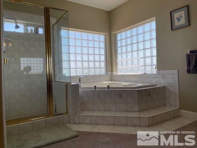 bathroom featuring plus walk in shower, a wealth of natural light, and tile patterned floors