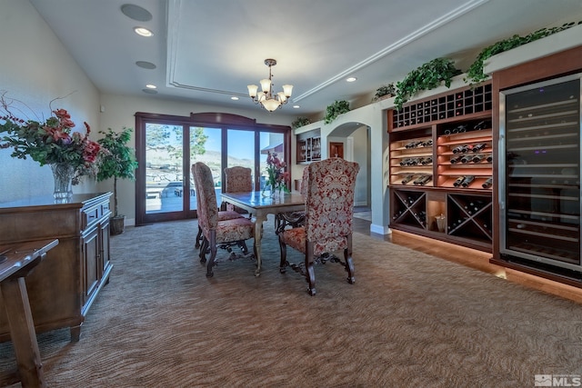 unfurnished dining area with dark carpet, an inviting chandelier, and wine cooler