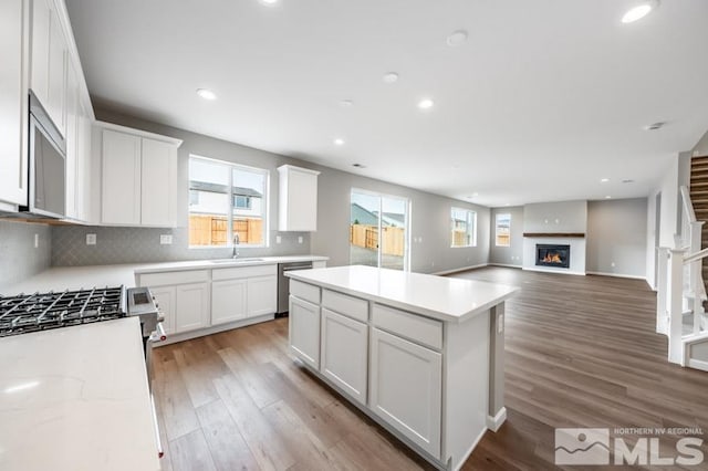 kitchen featuring white cabinetry, dishwasher, a center island, tasteful backsplash, and hardwood / wood-style floors