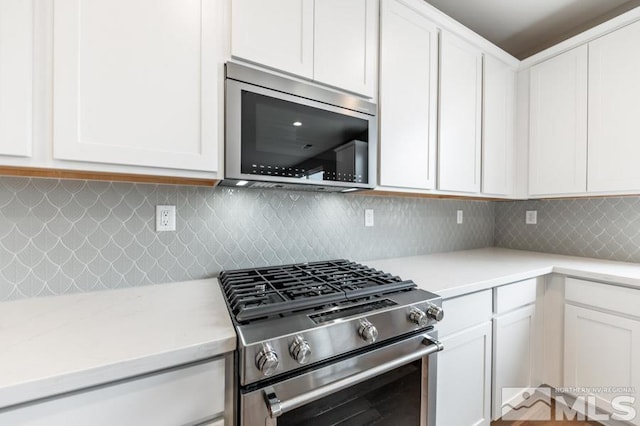 kitchen featuring white cabinets, decorative backsplash, and stainless steel appliances