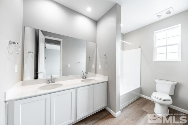 full bathroom featuring washtub / shower combination, toilet, vanity, and hardwood / wood-style flooring