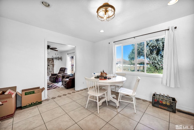 dining space with ceiling fan, light tile patterned floors, and a fireplace