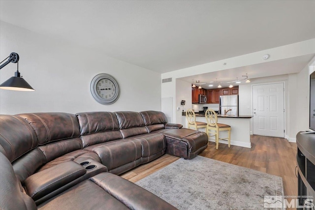 living area featuring wood finished floors, visible vents, and baseboards