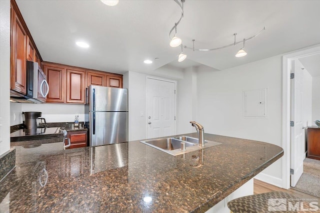 kitchen with stainless steel appliances, sink, kitchen peninsula, electric panel, and dark stone counters