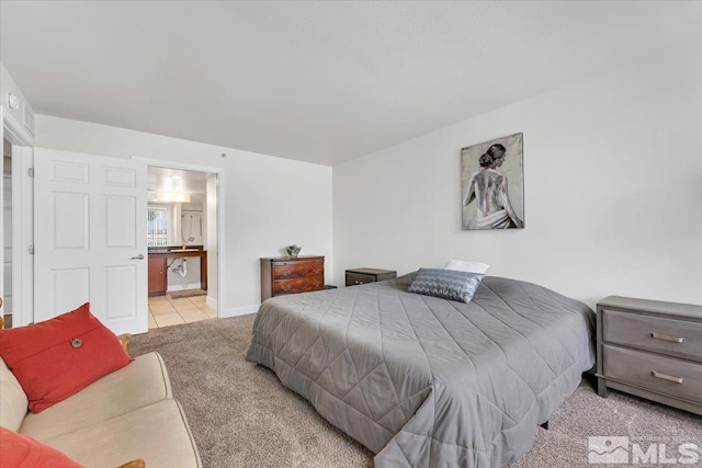 bedroom featuring light carpet and ensuite bathroom