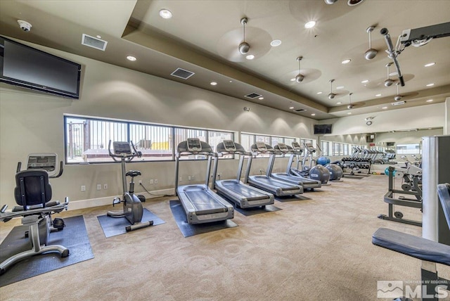 workout area featuring a raised ceiling, ceiling fan, a high ceiling, and carpet flooring