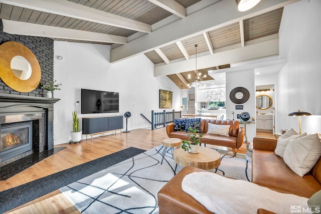 living room featuring a premium fireplace, a notable chandelier, wood ceiling, hardwood / wood-style flooring, and lofted ceiling with beams