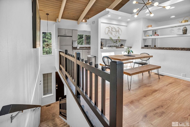 interior space featuring light hardwood / wood-style flooring, an inviting chandelier, wooden ceiling, and beam ceiling