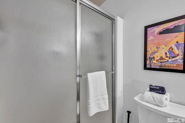 bathroom featuring a shower with door and toilet