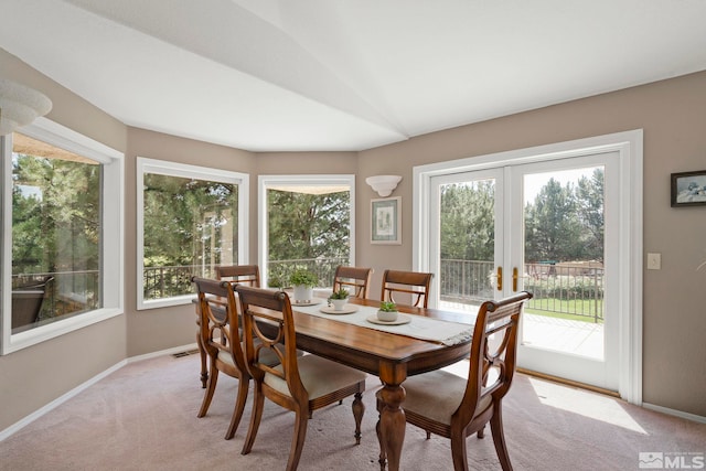 carpeted dining area featuring vaulted ceiling, plenty of natural light, and french doors