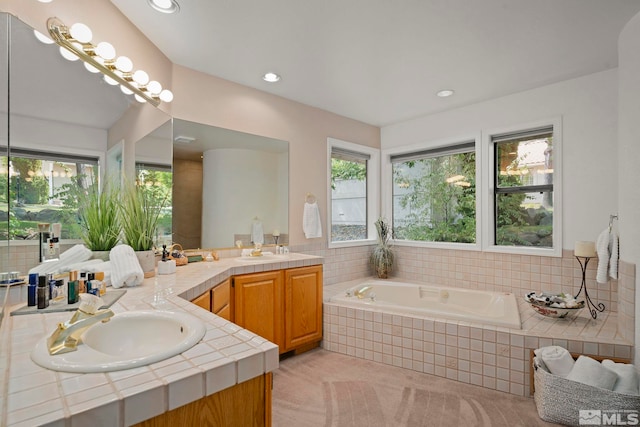 bathroom featuring vanity and tiled bath