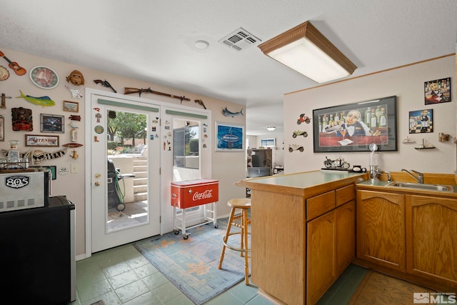 kitchen with a textured ceiling, kitchen peninsula, and sink