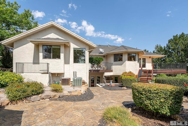 rear view of property with cooling unit, a wooden deck, and a patio area