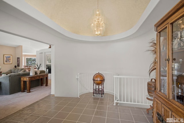 unfurnished dining area featuring tile patterned flooring, a raised ceiling, and a chandelier